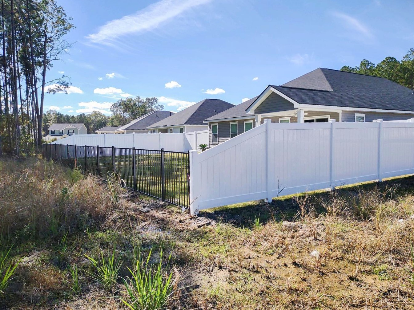 Photo of a white vinyl fence and a black aluminum fence together